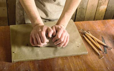 Creatrice Francaise faconnant la porcelaine a la main avec des outils sur un plan de travail